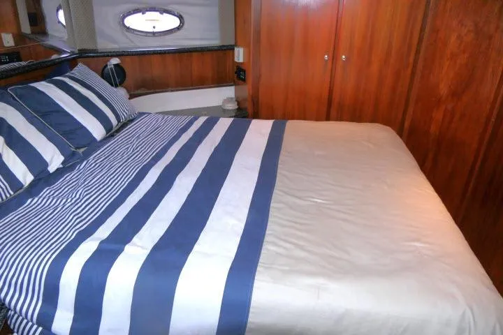 Code Four Yacht Photos Pics Interior of 2000 Carver 406 Motor Yacht with striped bedding and wooden cabinetry.