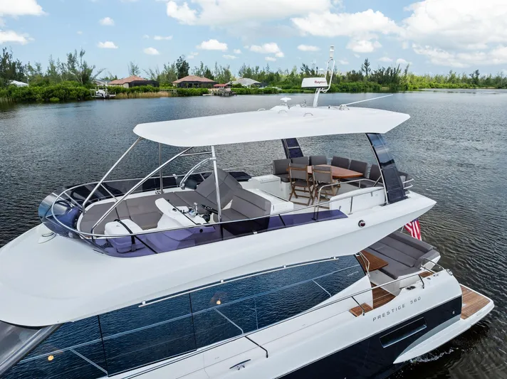  Yacht Photos Pics Prestige 560 Flybridge yacht, 2017 model, cruising on a serene lake under a blue sky.