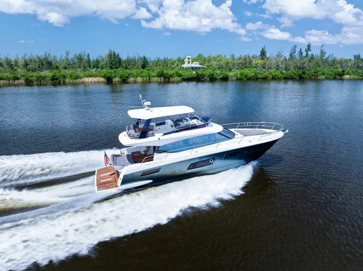  Yacht Photos Pics 2017 Prestige 560 Flybridge yacht cruising on a scenic river under a clear blue sky.