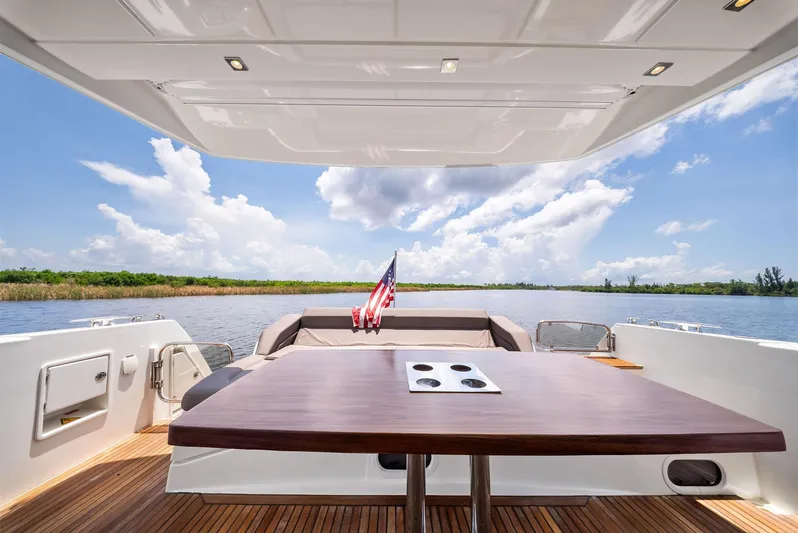 Yacht Photos Pics Prestige 560 Flybridge 2017 yacht deck with table, scenic water view, and American flag.