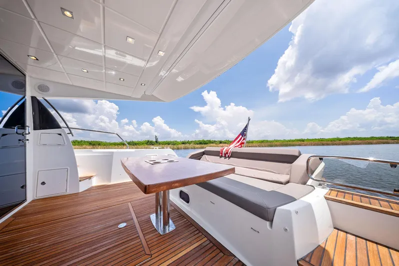  Yacht Photos Pics Prestige 560 Flybridge 2017 yacht deck with seating, table, and American flag.