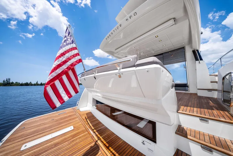  Yacht Photos Pics 2017 Prestige 560 Flybridge yacht with American flag, wooden deck, and clear blue sky.