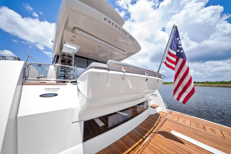  Yacht Photos Pics 2017 Prestige 560 Flybridge yacht with American flag, docked under a blue sky.