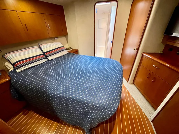  Yacht Photos Pics Cozy bedroom in 2000 Ocean Yachts 43 Super Sport with wooden cabinetry and blue bedding.