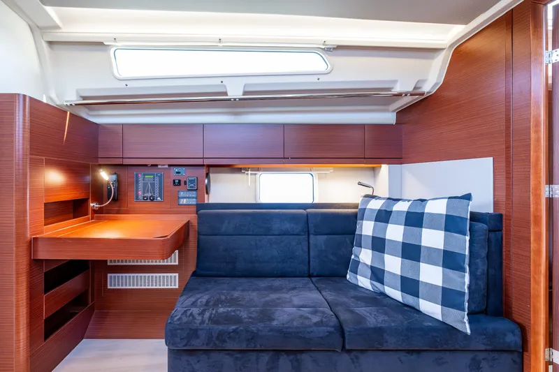 Dragon Fly Yacht Photos Pics 2019 Hanse 418 yacht interior with blue sofa, checkered pillow, and wooden desk.