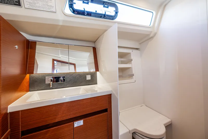 Dragon Fly Yacht Photos Pics 2019 Hanse 418 yacht bathroom with wooden cabinetry, sink, mirror, and toilet.