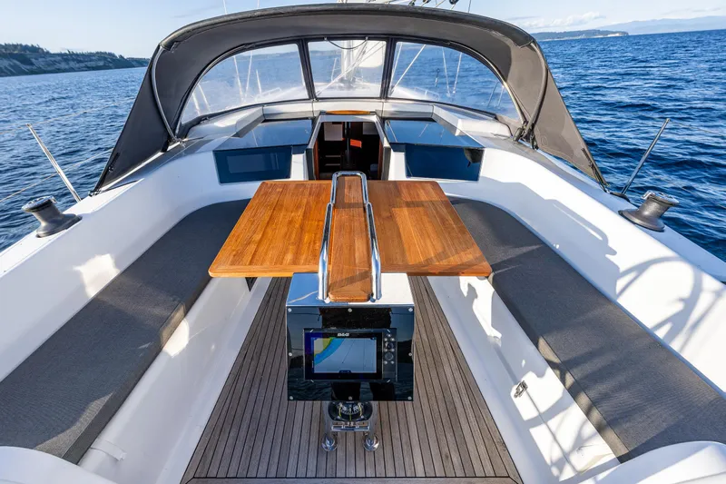 Dragon Fly Yacht Photos Pics 2019 Hanse 418 yacht cockpit with wooden table, cushioned seating, and navigation equipment on open water.