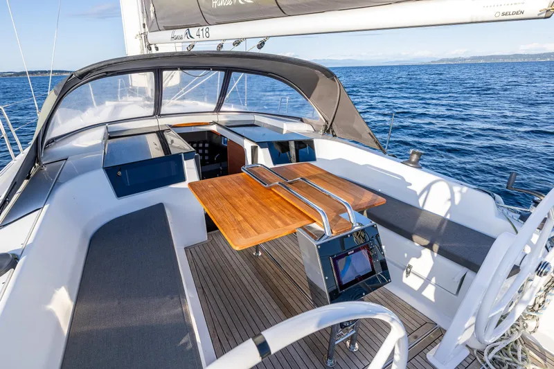 Dragon Fly Yacht Photos Pics 2019 Hanse 418 sailboat cockpit with wooden table, seating, and ocean view.
