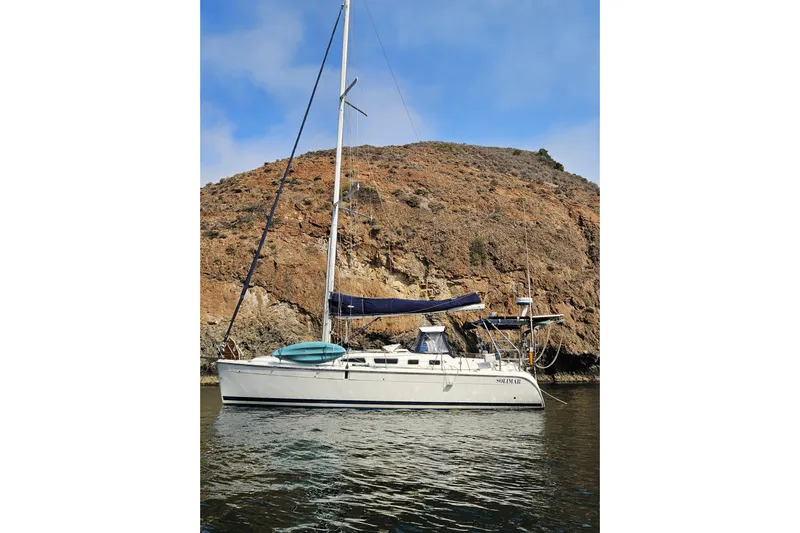 Solimar Yacht Photos Pics Sailboat Hunter 41 AC 2005 anchored near rocky coastline under clear sky.