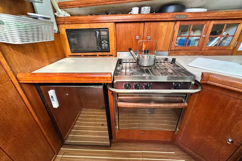 Solimar Yacht Photos Pics 2005 Hunter 41 AC yacht kitchen with stove, microwave, and wooden cabinetry.