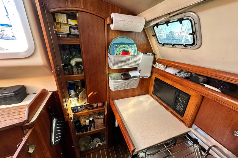 Solimar Yacht Photos Pics 2005 Hunter 41 AC yacht kitchen with wooden cabinets, microwave, and storage shelves.