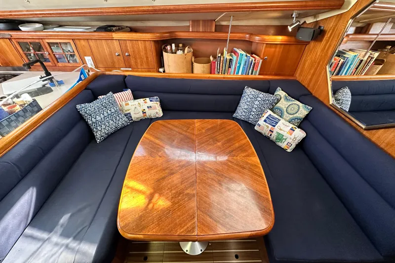 Solimar Yacht Photos Pics Cozy 2005 Hunter 41 AC yacht interior with wooden table, blue seating, and decorative pillows.