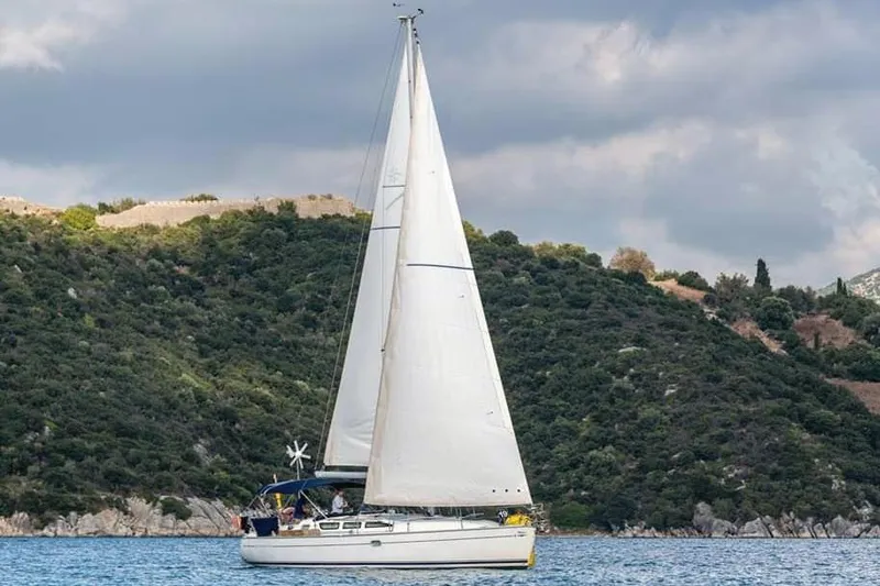  Yacht Photos Pics 2005 Jeanneau Sun Odyssey 40.3 sailing near lush green hills under cloudy skies.