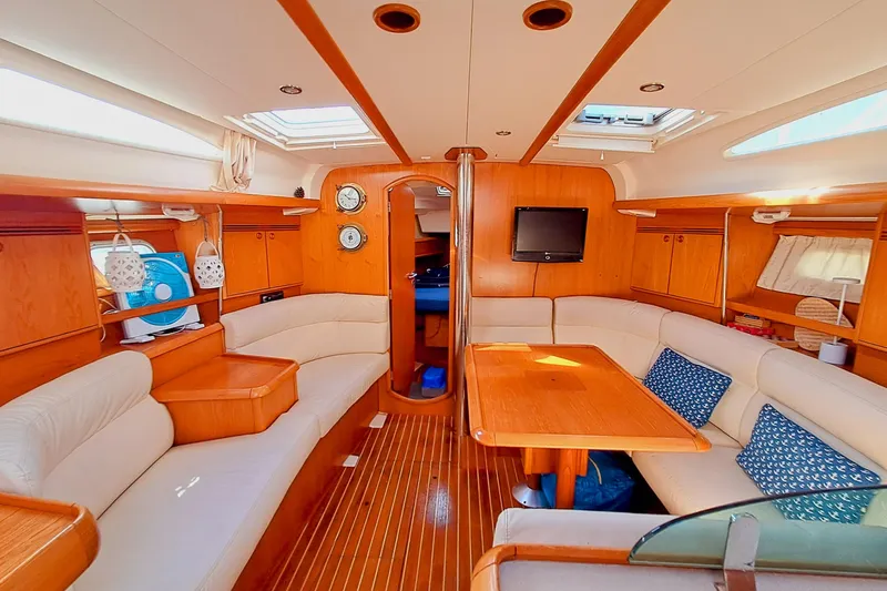  Yacht Photos Pics Luxurious interior of 2005 Jeanneau Sun Odyssey 40.3 sailboat with wood finish and seating area.