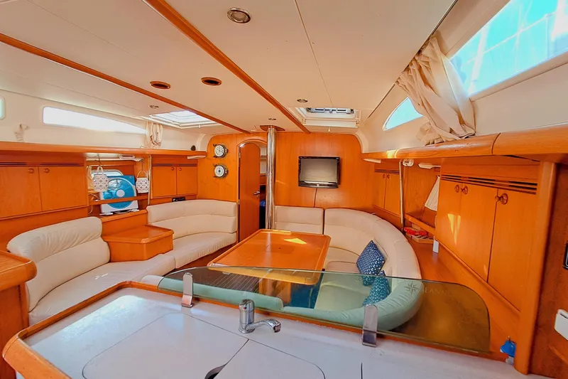  Yacht Photos Pics Luxurious interior of 2005 Jeanneau Sun Odyssey 40.3 sailboat with wood finish and seating area.