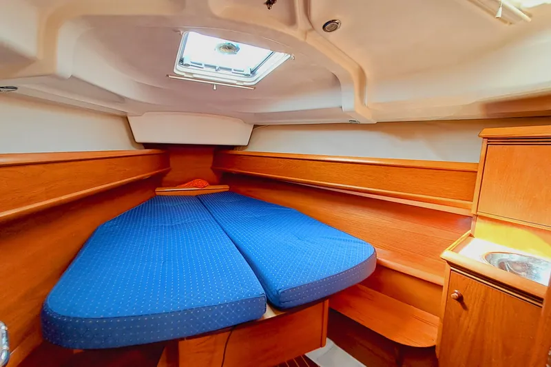  Yacht Photos Pics Cozy cabin interior of 2005 Jeanneau Sun Odyssey 40.3 with blue bedding and wooden finish.