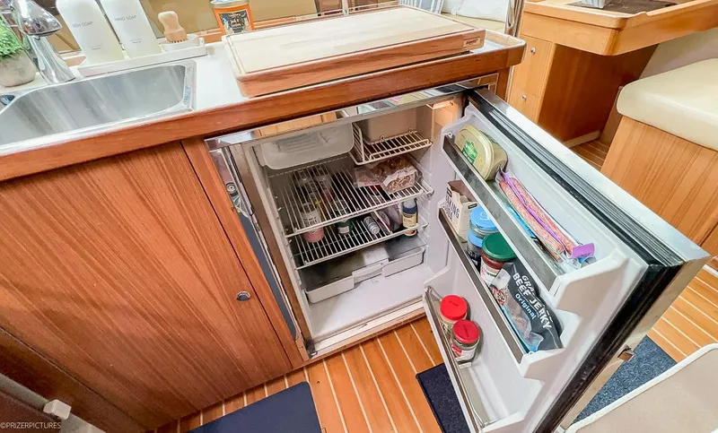 Kinship Ll Yacht Photos Pics Open refrigerator in a 2010 Catalina 445 yacht kitchen, showcasing organized food storage.