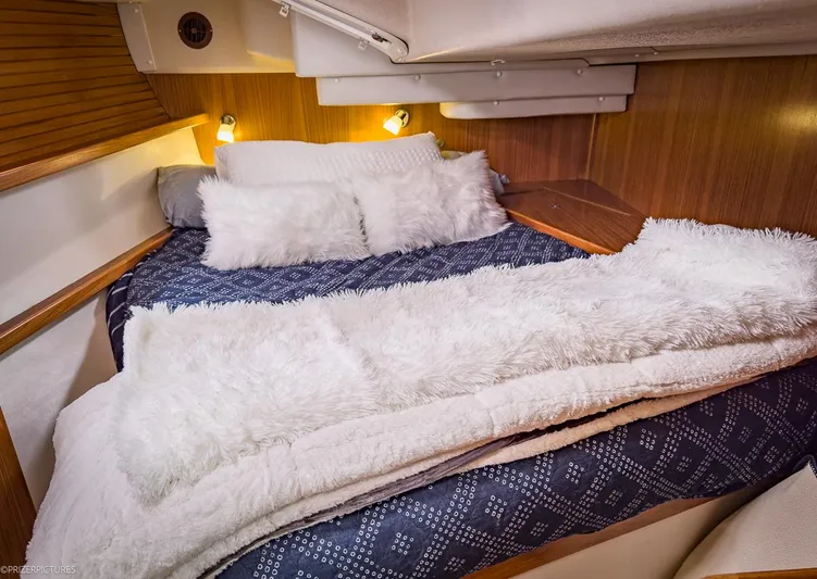 Kinship Ll Yacht Photos Pics Cozy cabin interior of 2010 Catalina 445 sailboat with plush bedding and warm lighting.