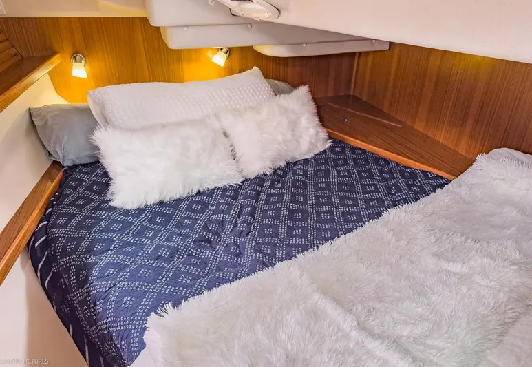 Kinship Ll Yacht Photos Pics Cozy cabin bed in 2010 Catalina 445 sailboat with plush pillows and soft lighting.