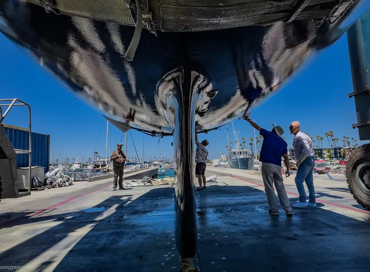 Kinship Ll Yacht Photos Pics People inspecting the underside of a 2010 Catalina 445 sailboat at a marina.