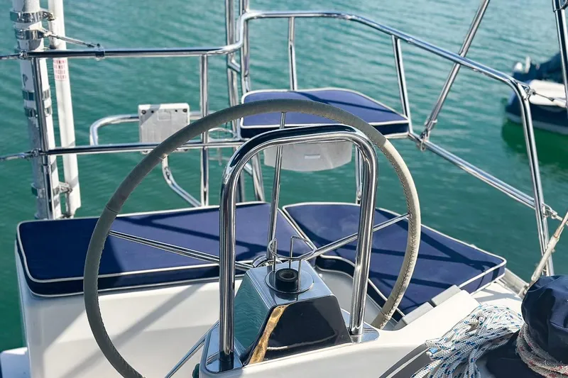 Kinship Ll Yacht Photos Pics Steering wheel of a 2010 Catalina 445 sailboat with blue cushions, docked on calm water.