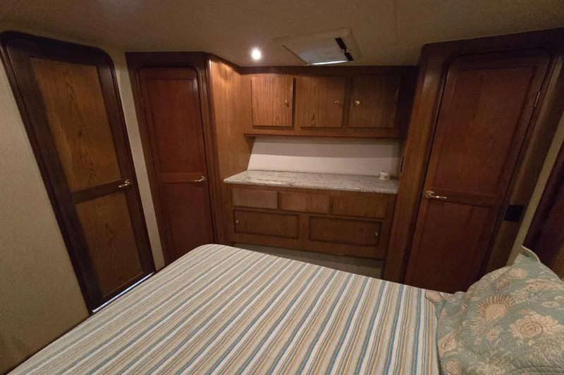  Yacht Photos Pics Interior cabin of 1986 Ocean Yachts 55 Super Sport with wooden cabinetry and striped bedding.