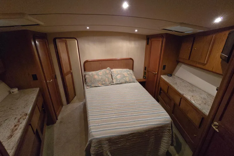  Yacht Photos Pics Luxurious bedroom interior of 1986 Ocean Yachts 55 Super Sport with cozy bed and wooden cabinetry.