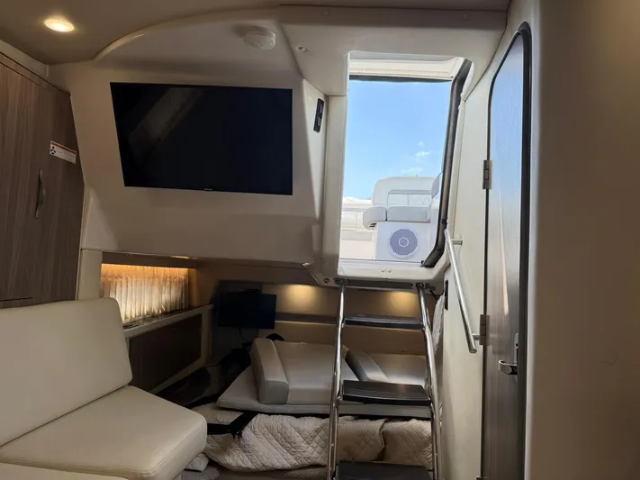  Yacht Photos Pics 2021 Regal 33 XO cabin interior with TV, seating, and ladder to deck.