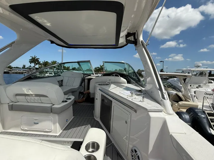  Yacht Photos Pics 2021 Regal 33 XO boat interior with seating and kitchenette under a clear blue sky.