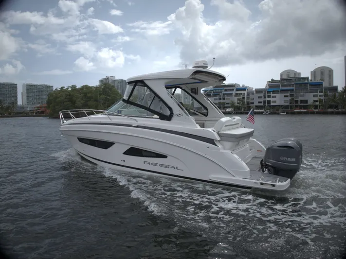  Yacht Photos Pics 2021 Regal 33 XO boat cruising on water with cityscape background.