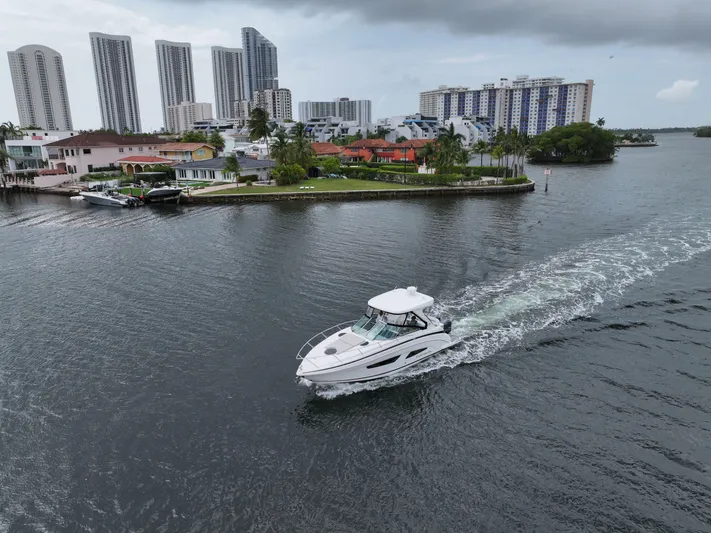  Yacht Photos Pics 2021 Regal 33 XO boat cruising near waterfront homes and high-rise buildings.