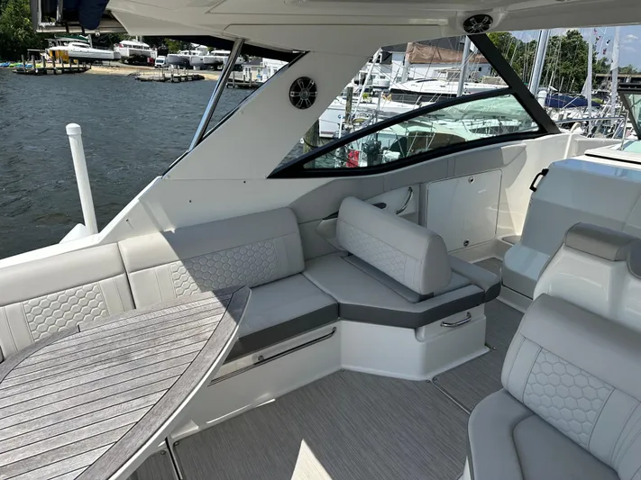  Yacht Photos Pics 2021 Sea Ray 320 Sundancer interior with elegant seating and wooden table, docked by the water.
