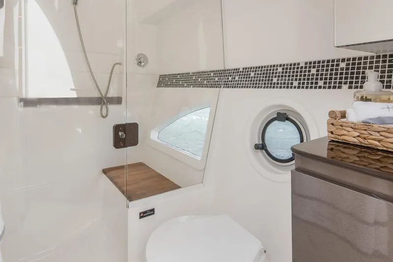  Yacht Photos Pics Modern bathroom interior in 2024 Hanover 415 Pure Gray yacht, featuring shower and porthole window.