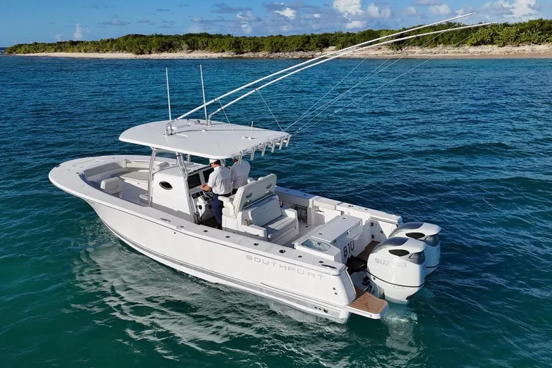  Yacht Photos Pics 2022 Southport 30 FE boat cruising on clear blue water near a lush shoreline.