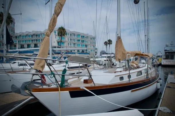 Sara Yacht Photos Pics Sailboat docked at marina, Passport 42 model, 1986, with covered sails and nearby buildings.