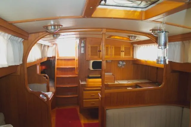 Sara Yacht Photos Pics Interior of 1986 Passport 42 sailboat with wooden cabinetry and cozy seating area.