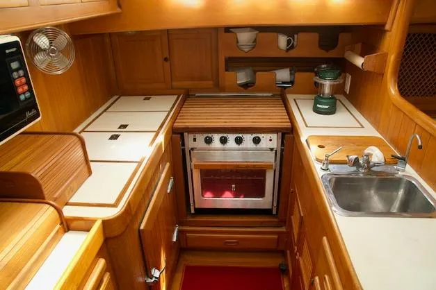 Sara Yacht Photos Pics Compact wooden kitchen interior on a 1986 Passport 42 yacht, featuring stove and sink.