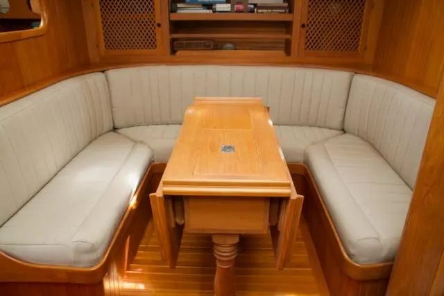Sara Yacht Photos Pics Cozy wooden interior of 1986 Passport 42 yacht with cushioned seating and table.