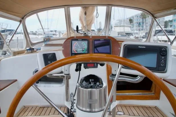 Sara Yacht Photos Pics Cockpit view of a 1986 Passport 42 sailboat with navigation instruments and wooden steering wheel.