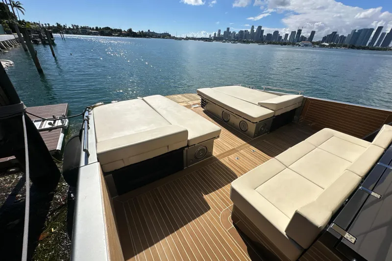 Yanina Yacht Photos Pics Luxury CNM 54 yacht deck with beige seating, overlooking city skyline and calm waters.