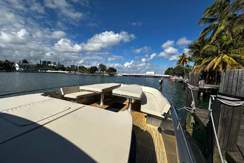 Yanina Yacht Photos Pics Luxurious 2019 CNM 54 yacht docked by palm trees under a vibrant blue sky.