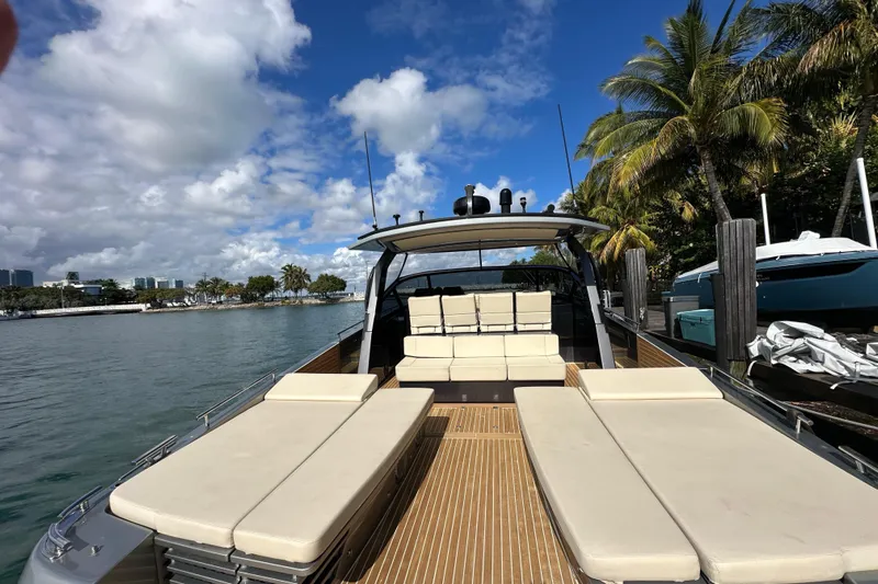 Yanina Yacht Photos Pics Luxurious 2019 CNM 54 yacht docked by palm trees under a clear blue sky.