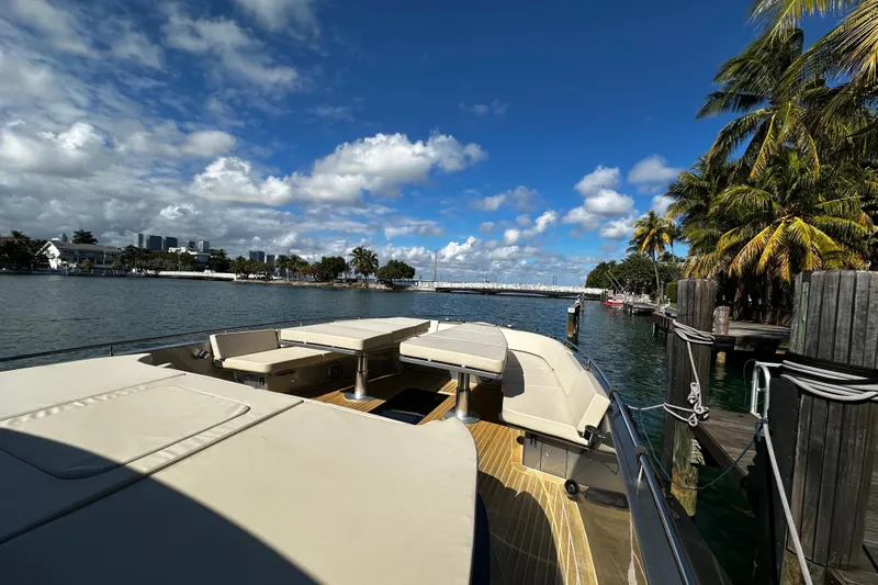 Yanina Yacht Photos Pics Luxurious 2019 CNM 54 yacht docked by palm trees under a vibrant blue sky.