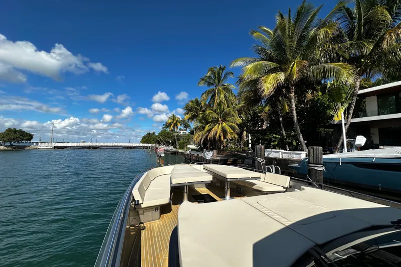 Yanina Yacht Photos Pics Luxurious CNM 54 yacht docked by palm trees, clear blue sky, and calm waters.
