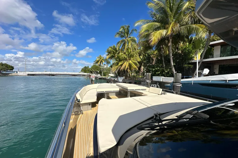 Yanina Yacht Photos Pics Luxurious CNM 54 yacht docked by palm trees, clear blue sky, and calm waters.
