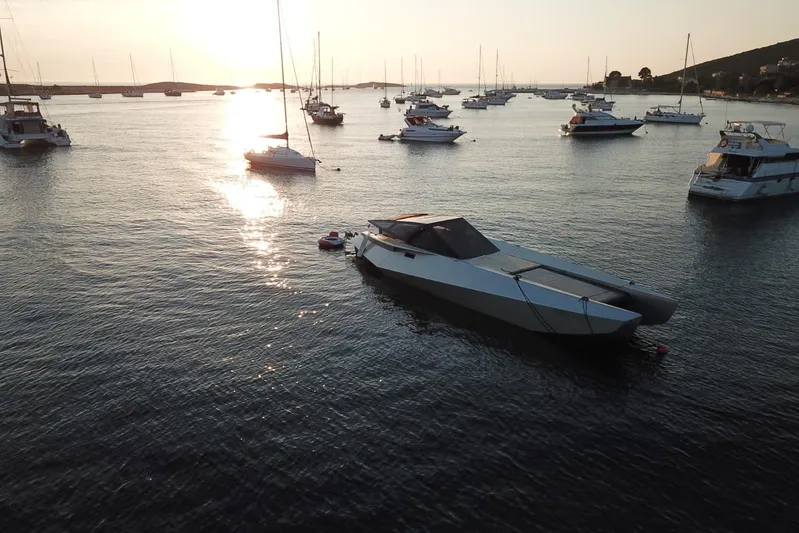 No Name Yacht Photos Pics Futuristic 2025 Offshore Racing Code X boat anchored at sunset in a serene harbor.