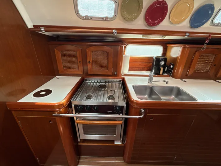 Gonzo Yacht Photos Pics Galley kitchen in 1997 Beneteau 50 yacht with stove, sink, and wooden cabinetry.