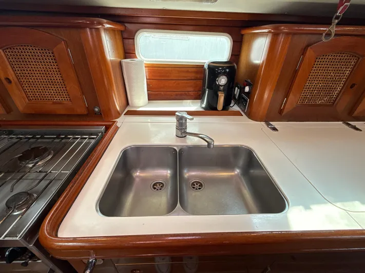 Gonzo Yacht Photos Pics 1997 Beneteau 50 yacht kitchen with double sink, wooden cabinets, and stove.