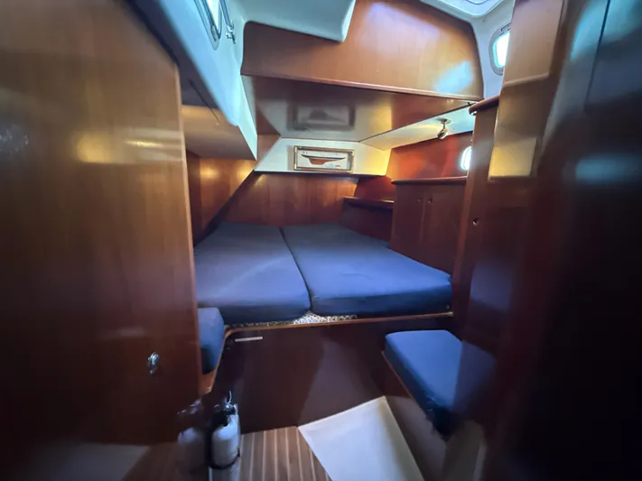Gonzo Yacht Photos Pics Cozy cabin interior of a 1997 Beneteau 50 sailboat with wooden finishes and blue cushions.