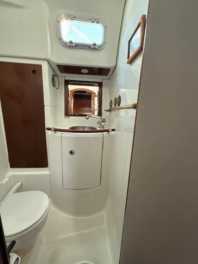Gonzo Yacht Photos Pics 1997 Beneteau 50 yacht bathroom with sink, toilet, and porthole window.